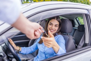 Car salesman giving key to new owner or customer